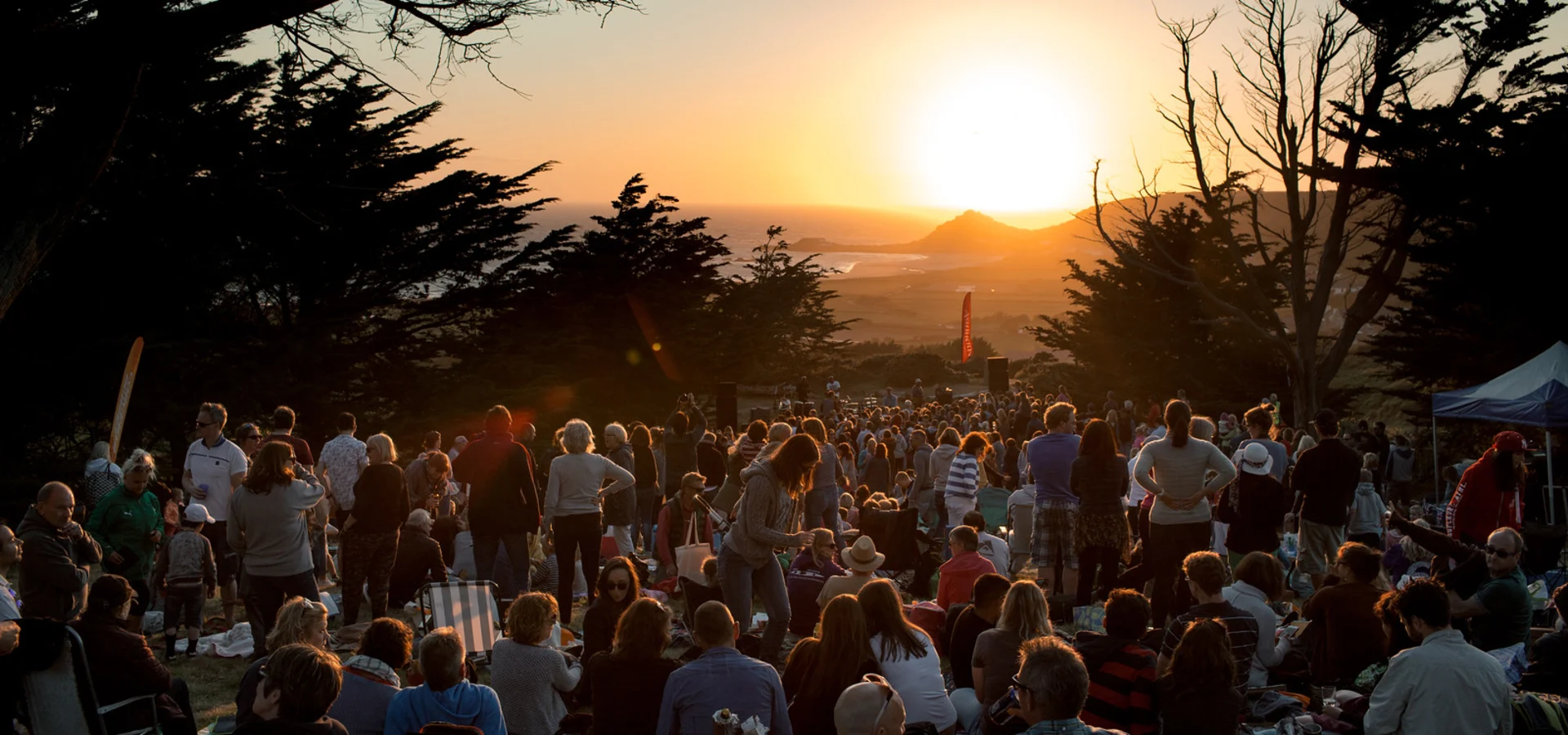 Sunset Concerts Jersey - sun sets over a crowd gathered in a woodland clearing